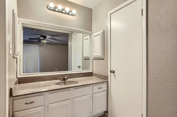 a bathroom with a granite countertop sink a mirror and a shower