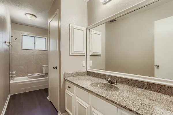 a bathroom with a granite countertop sink mirror and a bathtub