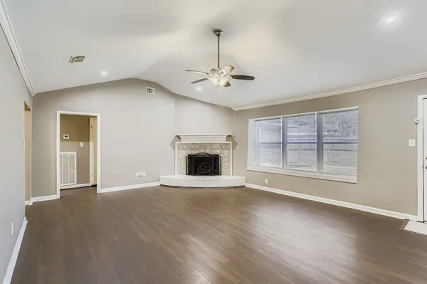 an empty room with wooden floor a ceiling fan and windows