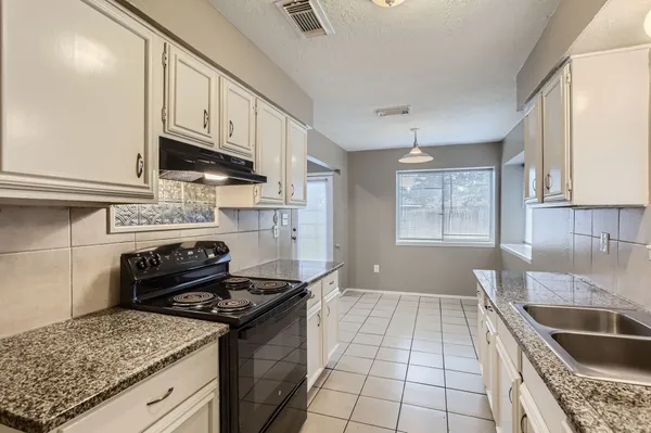 a kitchen with granite countertop a stove sink and cabinets