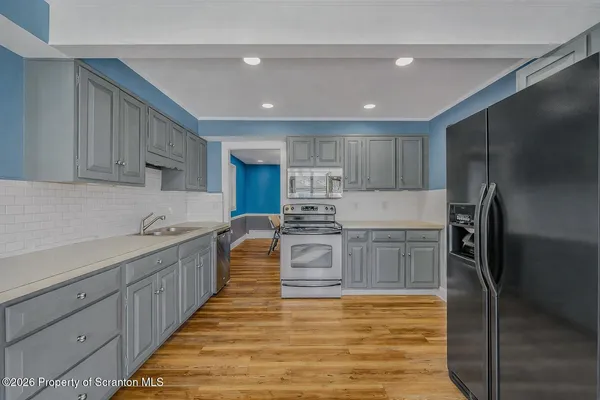 a large kitchen with stainless steel appliances kitchen island granite countertop a refrigerator and a stove top oven
