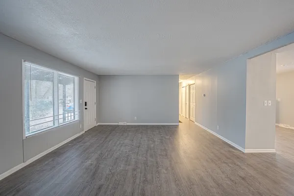 a view of an empty room with wooden floor and a window