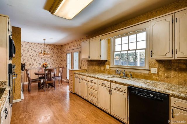 a kitchen with stainless steel appliances granite countertop wooden floors and white cabinets