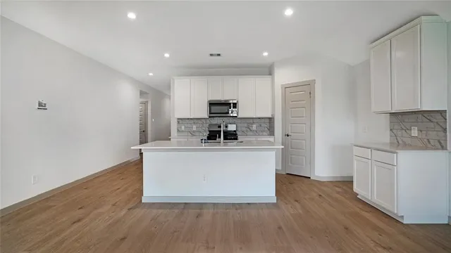 a kitchen with stainless steel appliances a white stove top oven cabinets and a wooden floor