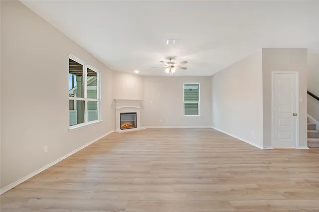 a view of an empty room with window and wooden floor