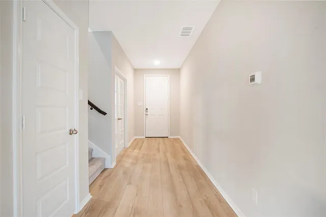 a view of a hallway with wooden floor and a bathroom