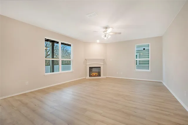 an empty room with windows and fireplace