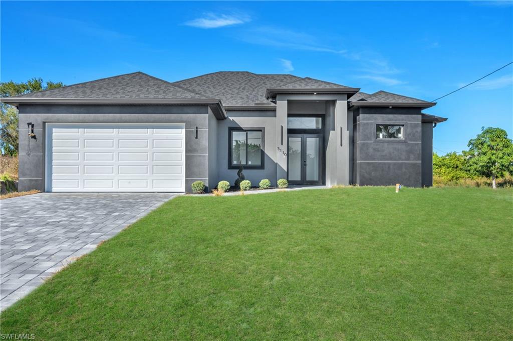 Prairie-style home with a front yard, stucco siding, decorative driveway, an attached garage, and a shingled roof