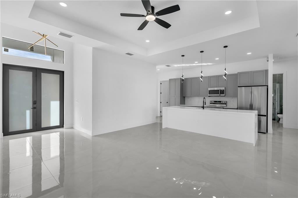 3110 23rd Street Southwest Lehigh Acres, FL 33976 - Photo 14 of 16 Unfurnished living room with a tray ceiling, recessed lighting, ceiling fan, and french doors