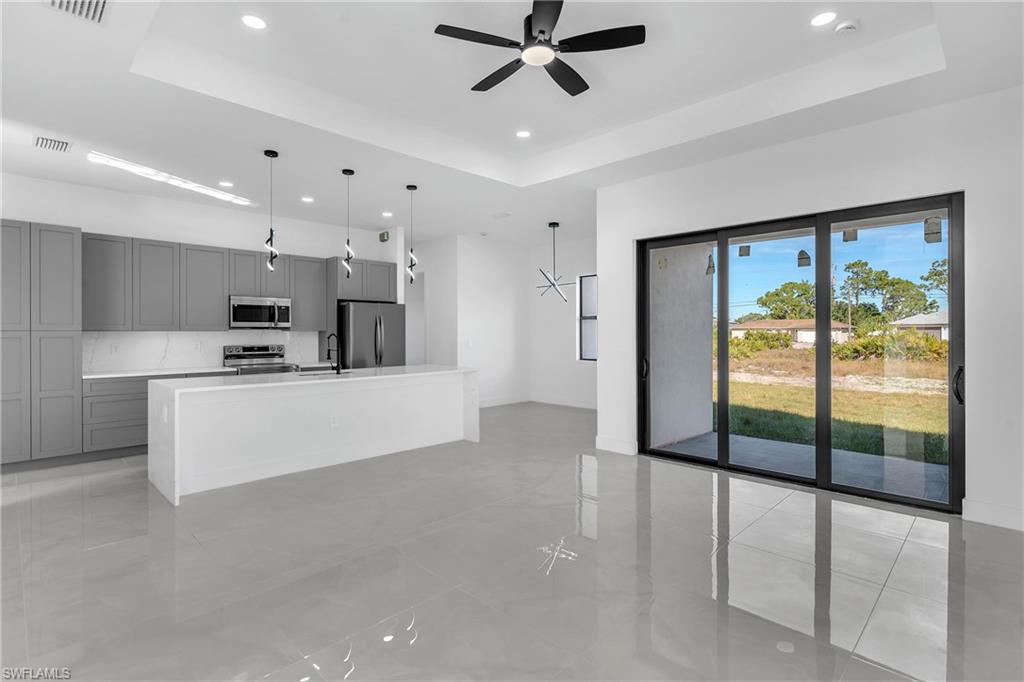 3110 23rd Street Southwest Lehigh Acres, FL 33976 - Photo 15 of 16 Unfurnished living room featuring a tray ceiling, recessed lighting, and ceiling fan