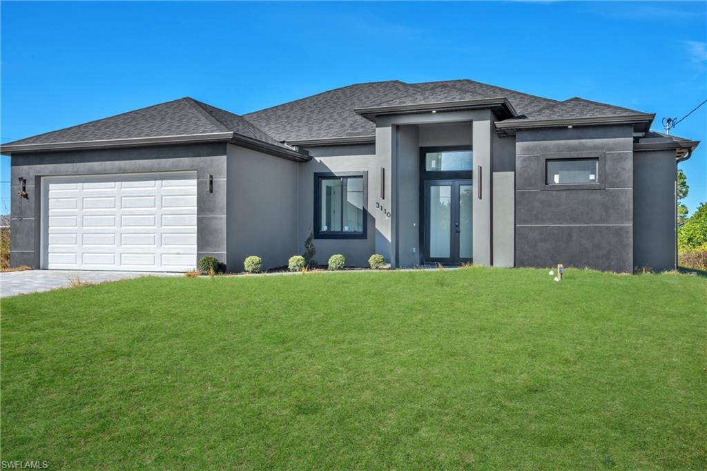 3110 23rd Street Southwest Lehigh Acres, FL 33976 - Photo 2 of 16 Prairie-style house featuring a front yard, stucco siding, roof with shingles, and a garage