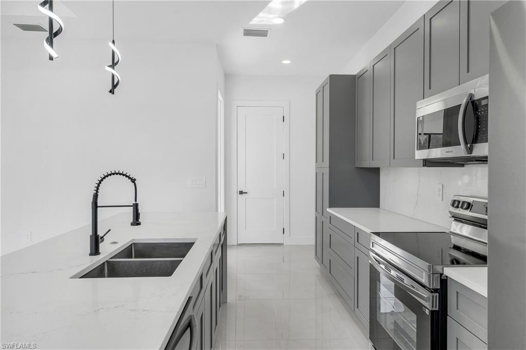 3110 23rd Street Southwest Lehigh Acres, FL 33976 - Photo 6 of 16 Kitchen with appliances with stainless steel finishes, gray cabinetry, light stone countertops, and recessed lighting
