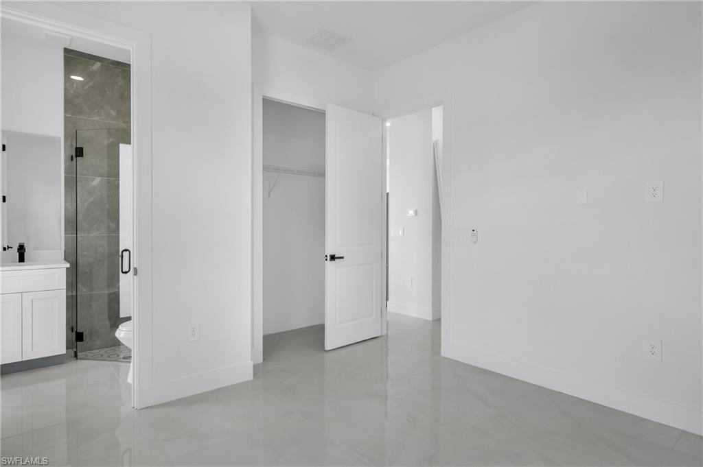 3110 23rd Street Southwest Lehigh Acres, FL 33976 - Photo 10 of 16 Unfurnished bedroom featuring connected bathroom and a sink