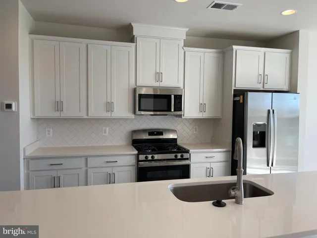 a kitchen with granite countertop white cabinets and stainless steel appliances