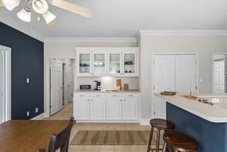 a large white kitchen with granite countertop a stove a sink a dining table and chairs
