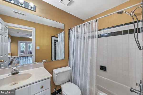 a bed sitting in a spacious bedroom next to a large window with a potted plant on the dresser