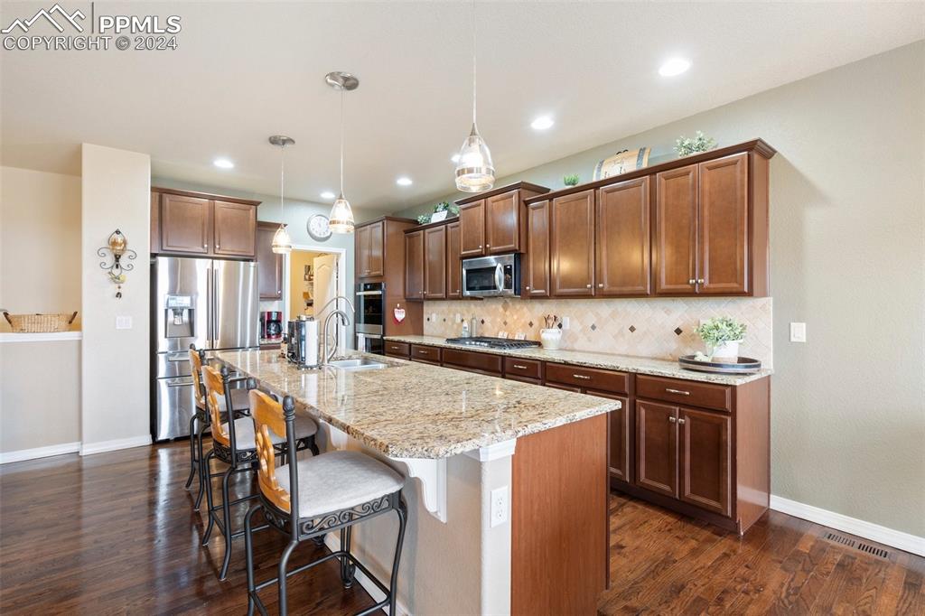 11501 Palmers Green Drive Peyton, CO 80831 - Photo 21 of 49 a kitchen with stainless steel appliances granite countertop a table chairs sink refrigerator and microwave