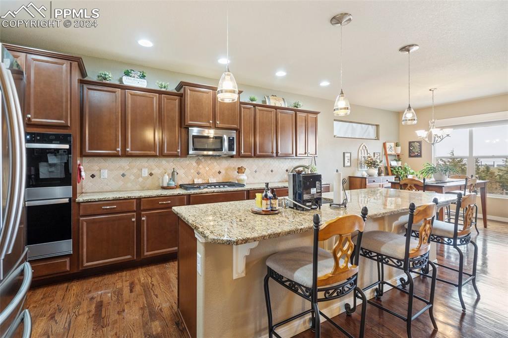 11501 Palmers Green Drive Peyton, CO 80831 - Photo 22 of 49 a kitchen with stainless steel appliances granite countertop a stove top oven a refrigerator a sink and chairs