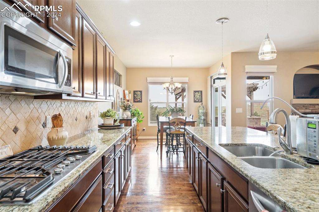 11501 Palmers Green Drive Peyton, CO 80831 - Photo 25 of 49 a kitchen with granite countertop a stove a sink and a wooden cabinets