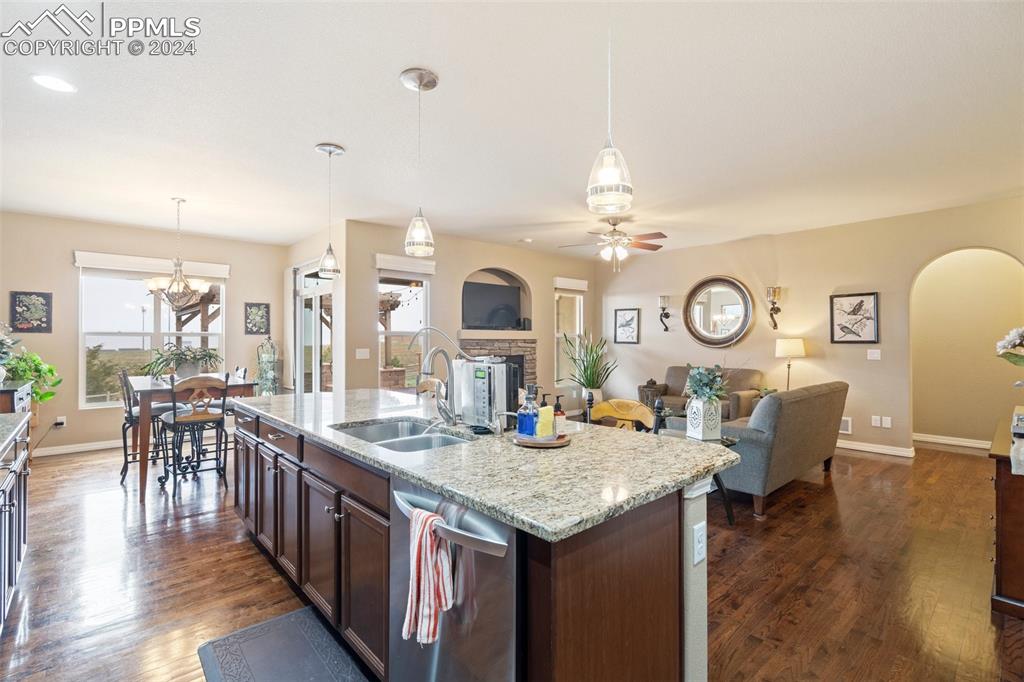 11501 Palmers Green Drive Peyton, CO 80831 - Photo 26 of 49 a living room with granite countertop kitchen island stainless steel appliances furniture a fireplace and a dining table with wooden floor