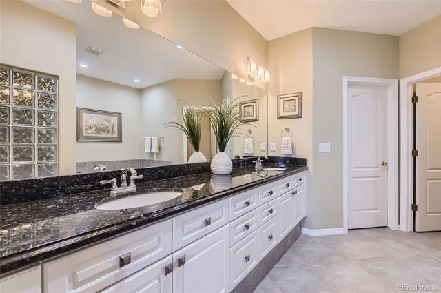 a bathroom with double vanity sinks a vanity a lamp and a window