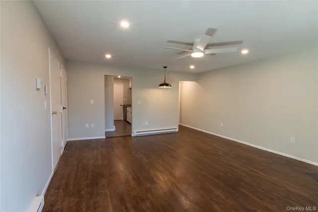 an empty room with wooden floor and a ceiling fan