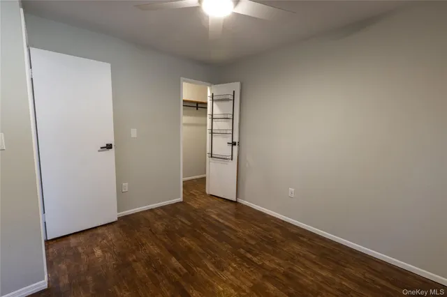 an empty room with wooden floor closet and windows
