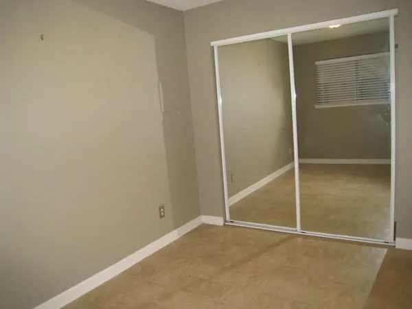 a view of an empty room with closet and a bathroom