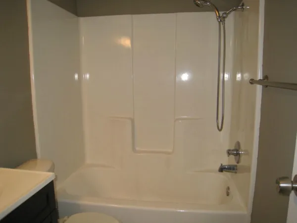an empty room with wooden floor closet and windows