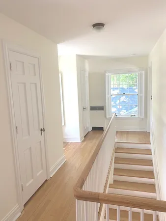 a view of a hallway with wooden floor and windows