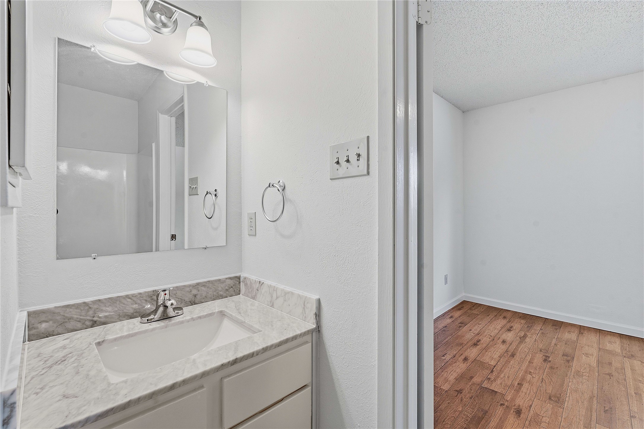 6205 Shadow Bend Austin, TX 78745 - Photo 22 of 31 A well-appointed vanity with a sleek countertop and a brightly lit mirror graces this refreshed bathroom.
