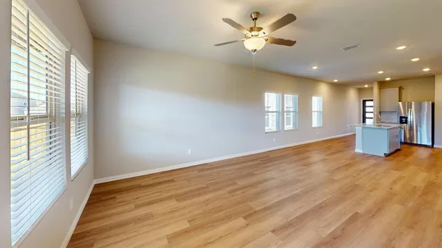 a view of an empty room with a window and wooden floor