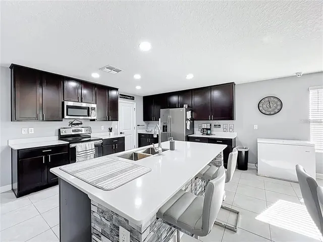 a kitchen with kitchen island wooden cabinets a refrigerator stove a sink and a oven