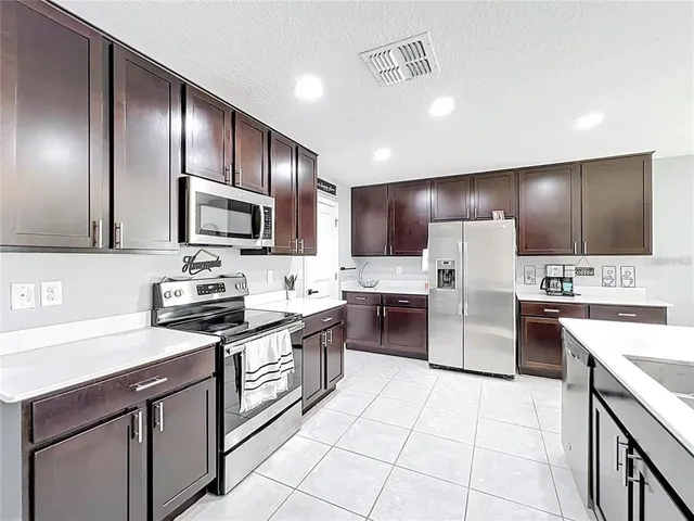 a kitchen with stainless steel appliances kitchen island granite countertop a stove refrigerator sink and microwave