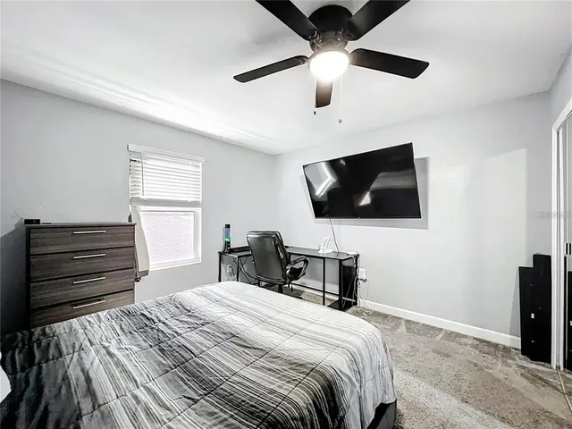a bedroom with a bed a tv and wooden floor