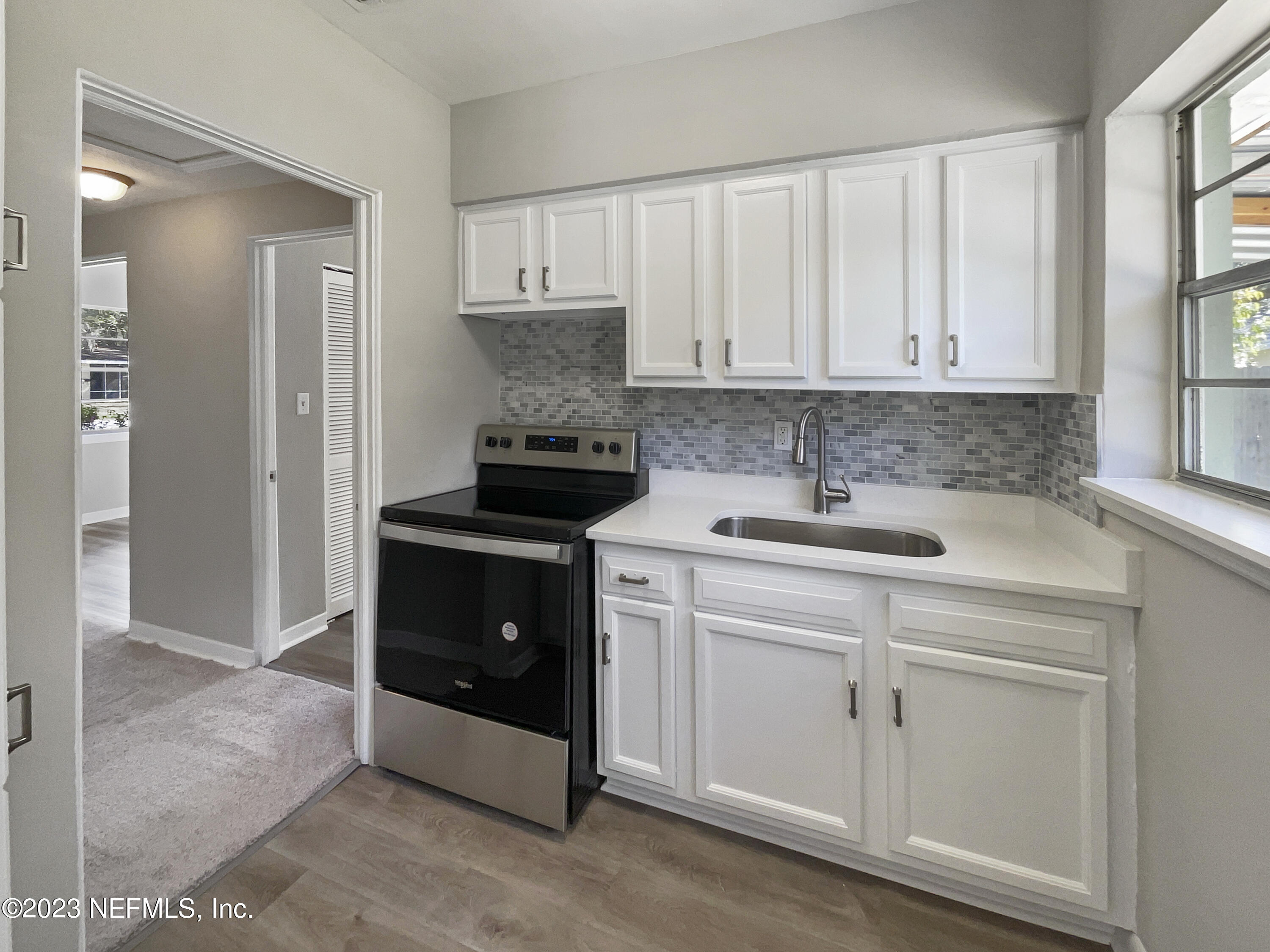 5624 Orangewood Road Jacksonville, FL 32207 - Photo 8 of 19 a kitchen with white cabinets and a stove with wooden floor