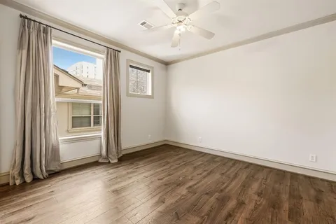 an empty room with wooden floor fan and windows