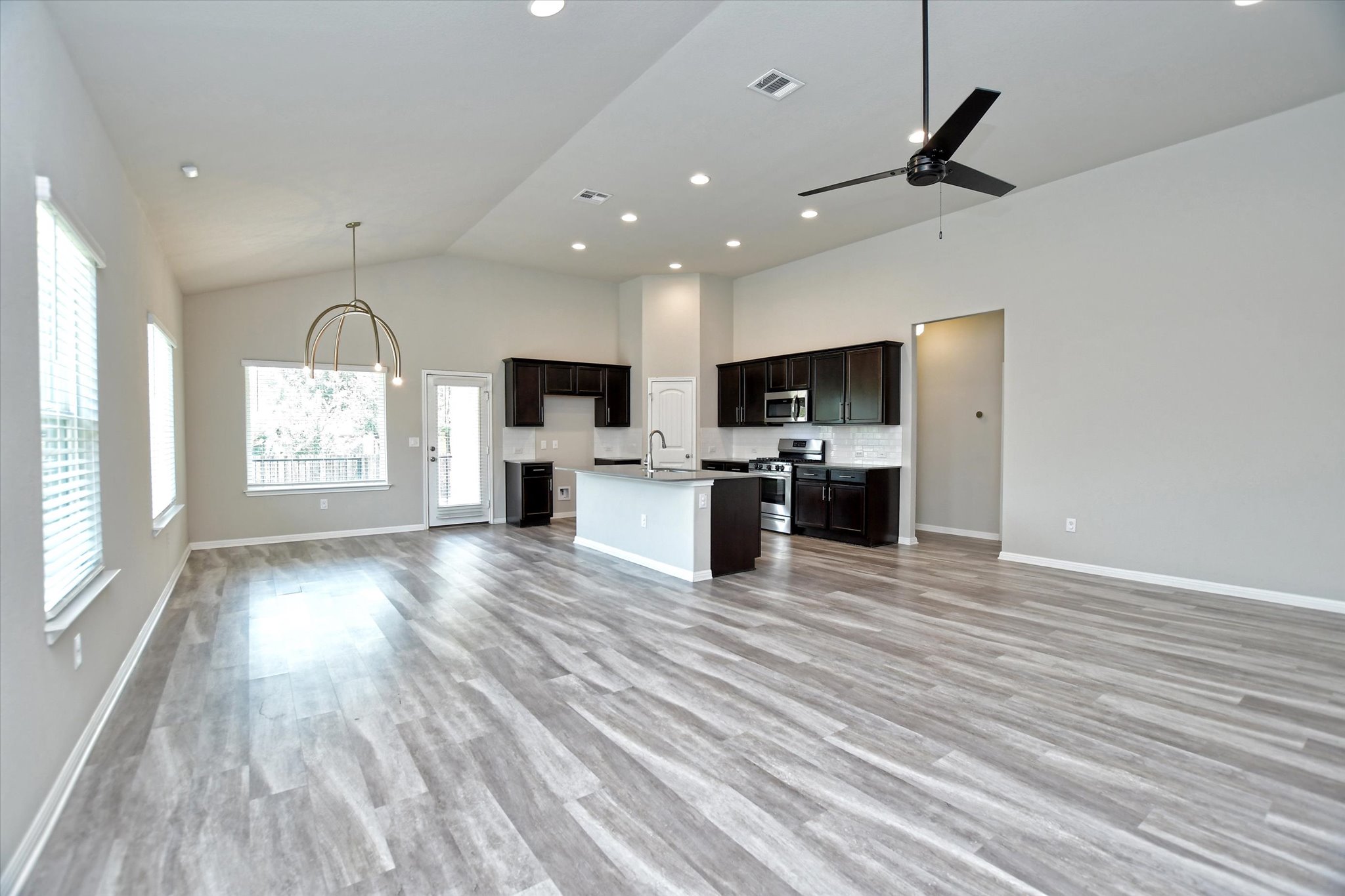 An open-concept living space integrates a well-appointed kitchen with rich cabinetry and stainless steel appliances.