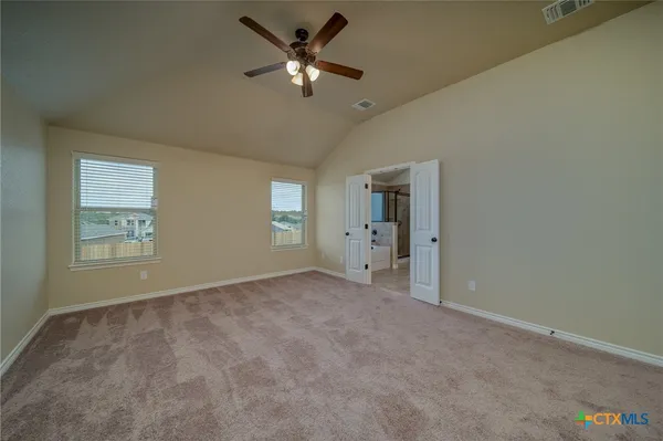 an empty room with windows and fan