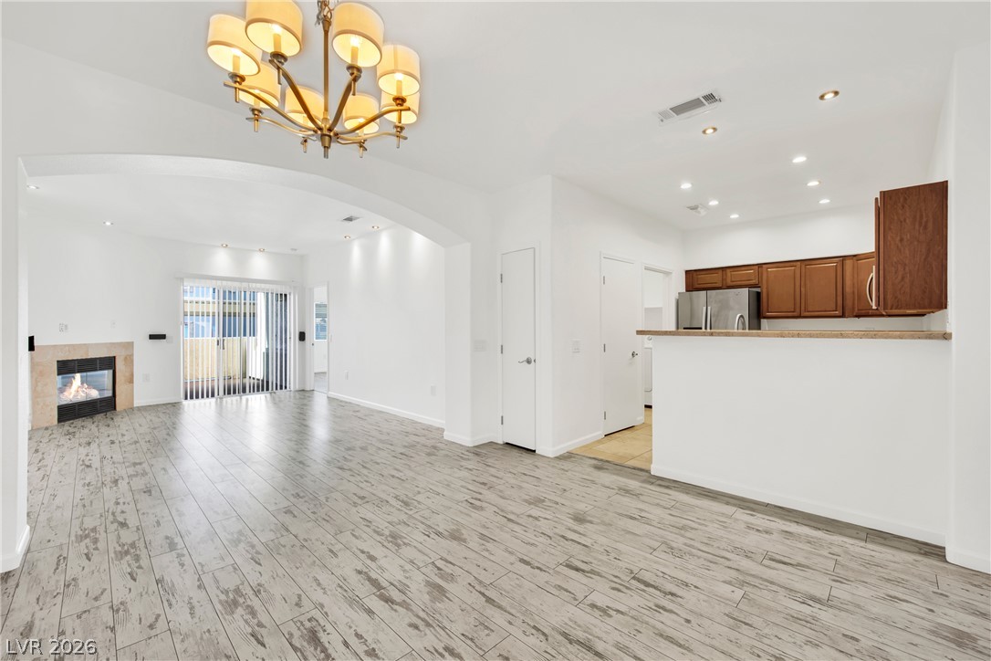 8725 West Flamingo Road, Unit 110 Las Vegas, NV 89147 - Photo 24 of 30 A spacious living area with warm wood-look flooring and a cozy fireplace, seamlessly connecting to a modern kitchen.