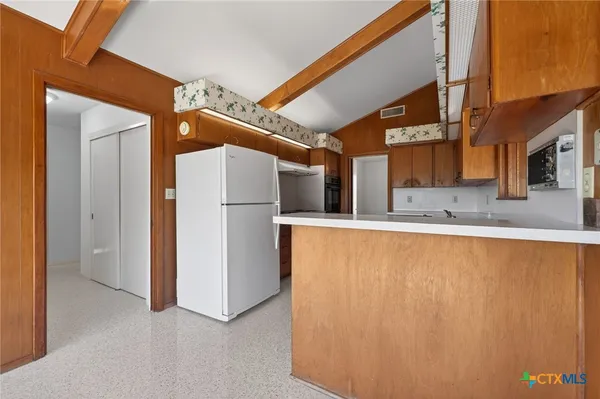 a view of kitchen with refrigerator and cabinets