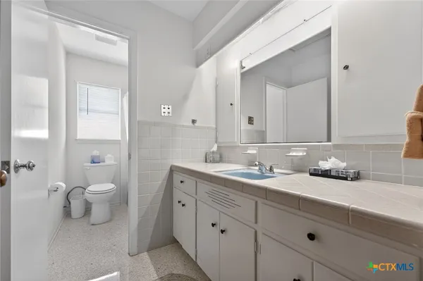 a bathroom with a toilet a sink and mirror