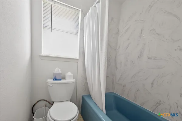 a white toilet sitting next to a shower curtain