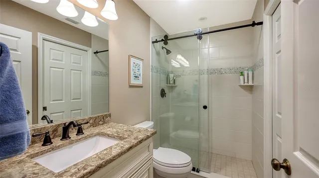 a bathroom with a granite countertop shower sink vanity mirror and toilet