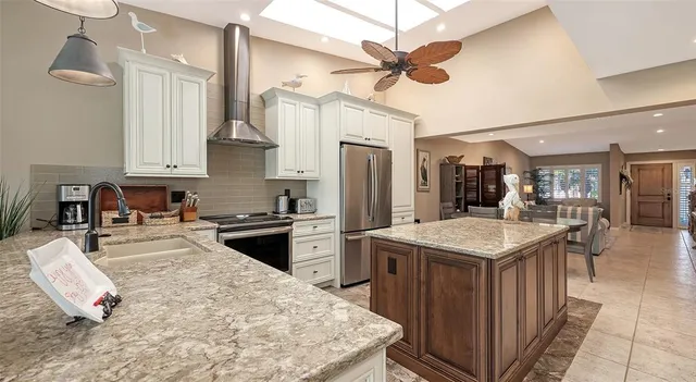 a kitchen with stainless steel appliances kitchen island a table chairs refrigerator and microwave
