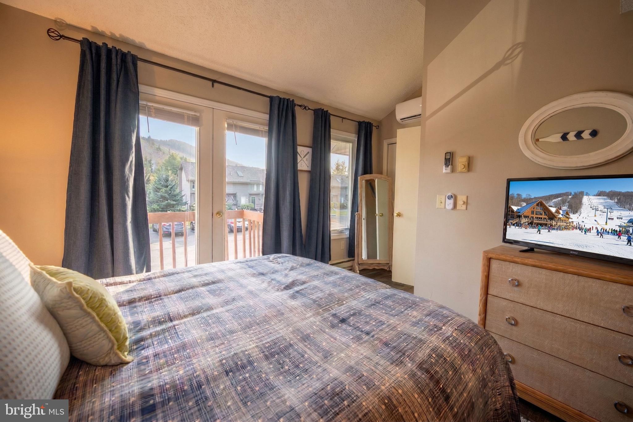 257 Marsh Hill Road, Unit 27 McHenry, MD 21541 - Photo 29 of 64 a bedroom with a bed a dresser and a large window