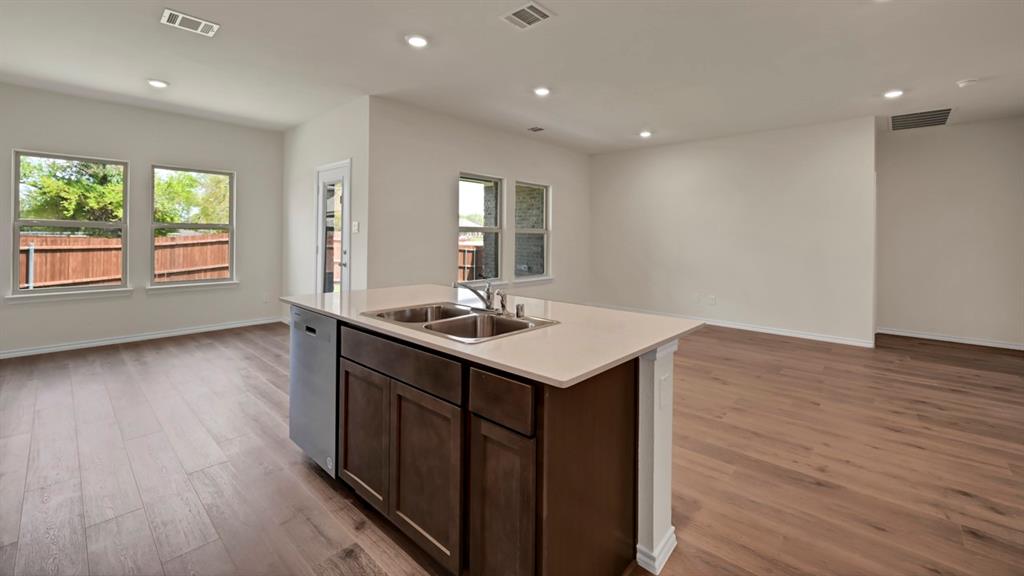 4012 Ripplewood Drive Lindale, TX 75771 - Photo 22 of 37 Kitchen island featuring a double-basin stainless steel sink, integrated dishwasher, and light-toned countertop