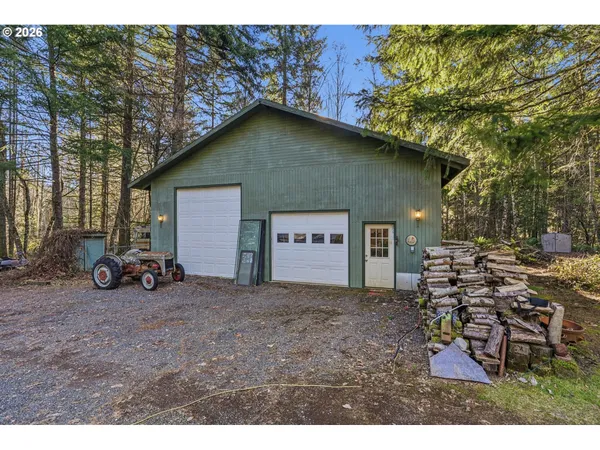 a view of a house with large trees and a car parked beside it