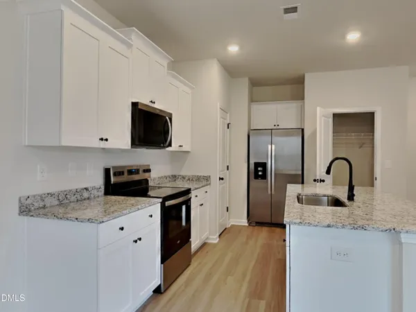 a kitchen with granite countertop a refrigerator stove top oven and sink