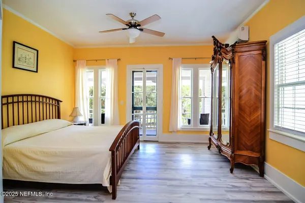 a bedroom with a bed next to a large window with wooden floor